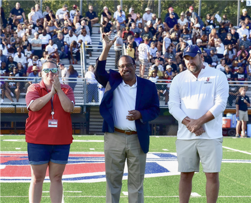 Alfred Watkins holding award on football field