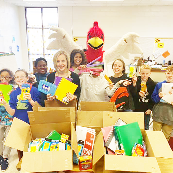 Students holding donated schools supplies 
